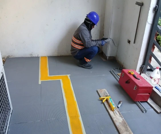 Técnico electricista realizando mantenimiento preventivo y señalización de seguridad en cuarto técnico industrial, cumpliendo con protocolos de organización y protección.