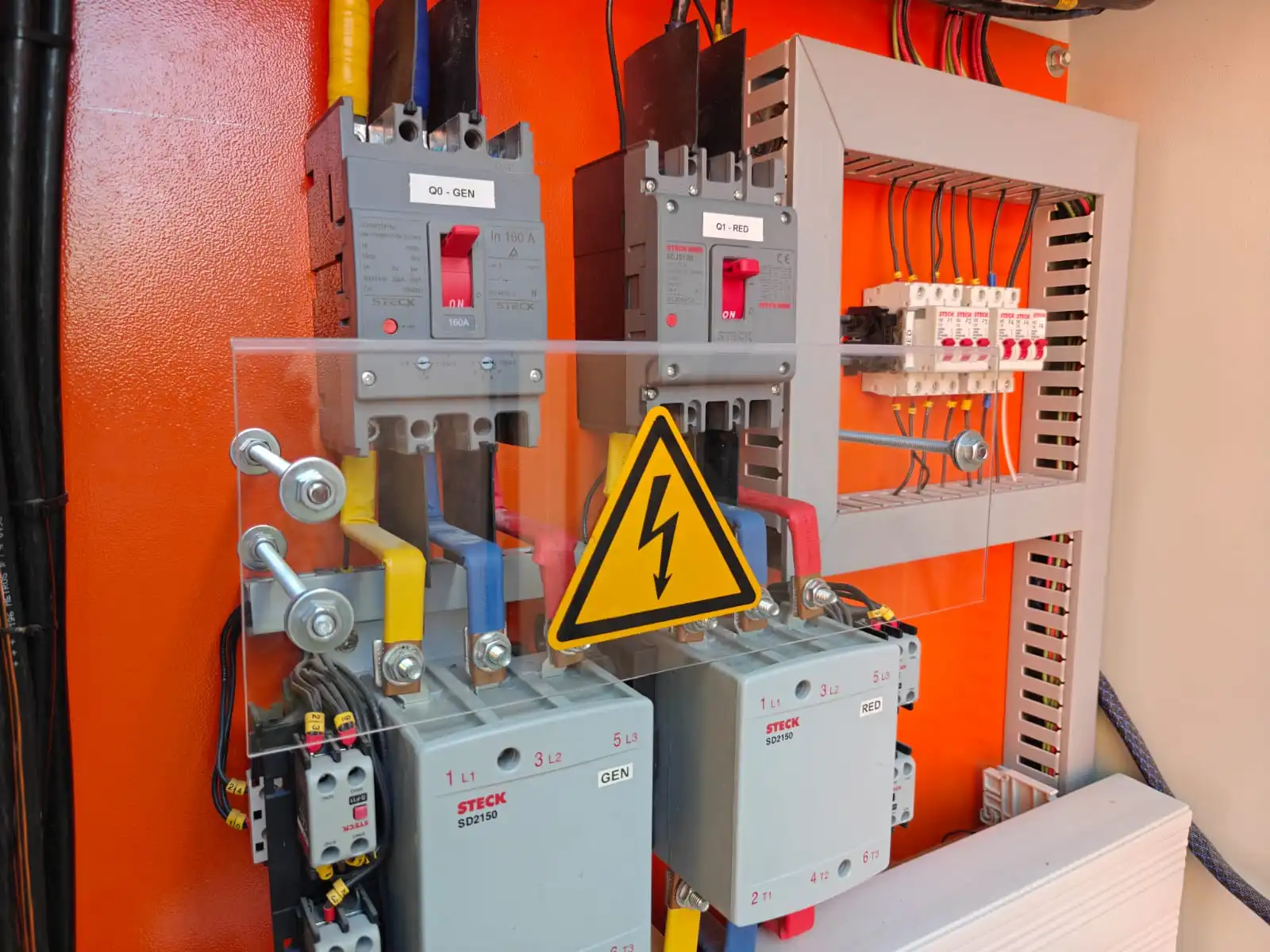 Montaje técnico de contactores y disyuntores de caja moldeada marca Steck con barras de distribución aisladas y protección acrílica de seguridad.