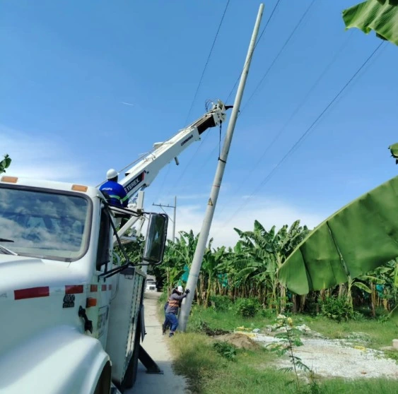 Instalación de redes eléctricas de media tensión mediante camión canasta y personal técnico en postes de concreto.
